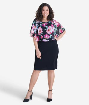 Woman posing wearing Black Alyssa Floral Cape Dress from Connected Apparel