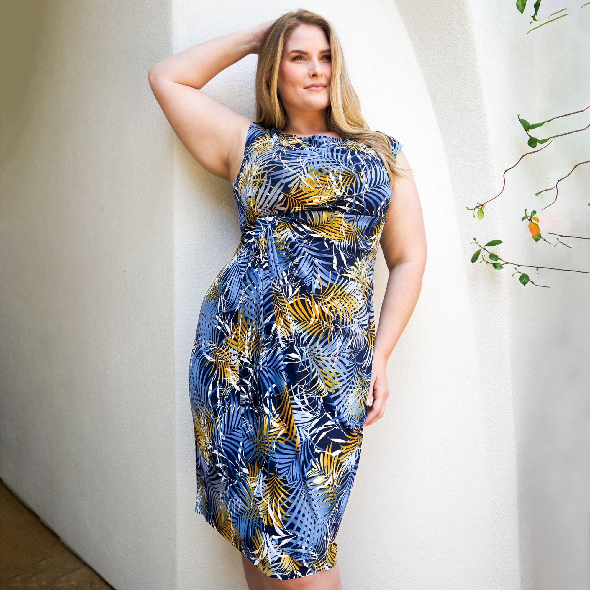 Woman posing wearing Navy/Mustard Lisa Palm Print Faux Wrap Dress from Connected Apparel