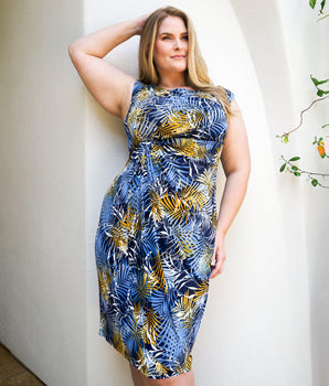 Woman posing wearing Navy/Mustard Lisa Palm Print Faux Wrap Dress from Connected Apparel