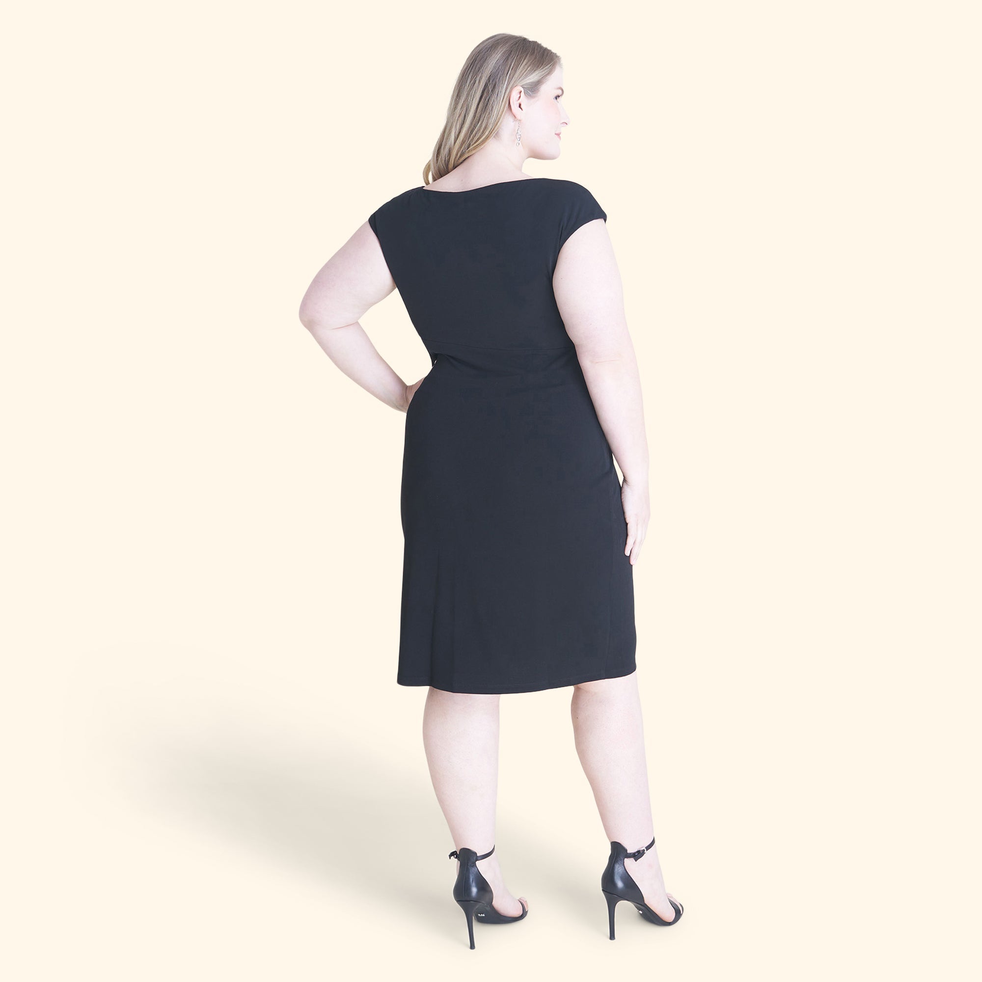 Woman posing wearing Black Lisa Sleeveless Black Faux Wrap Dress from Connected Apparel