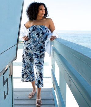 Woman posing wearing Navy Melissa Leaf Print Strapless Jumpsuit from Connected Apparel